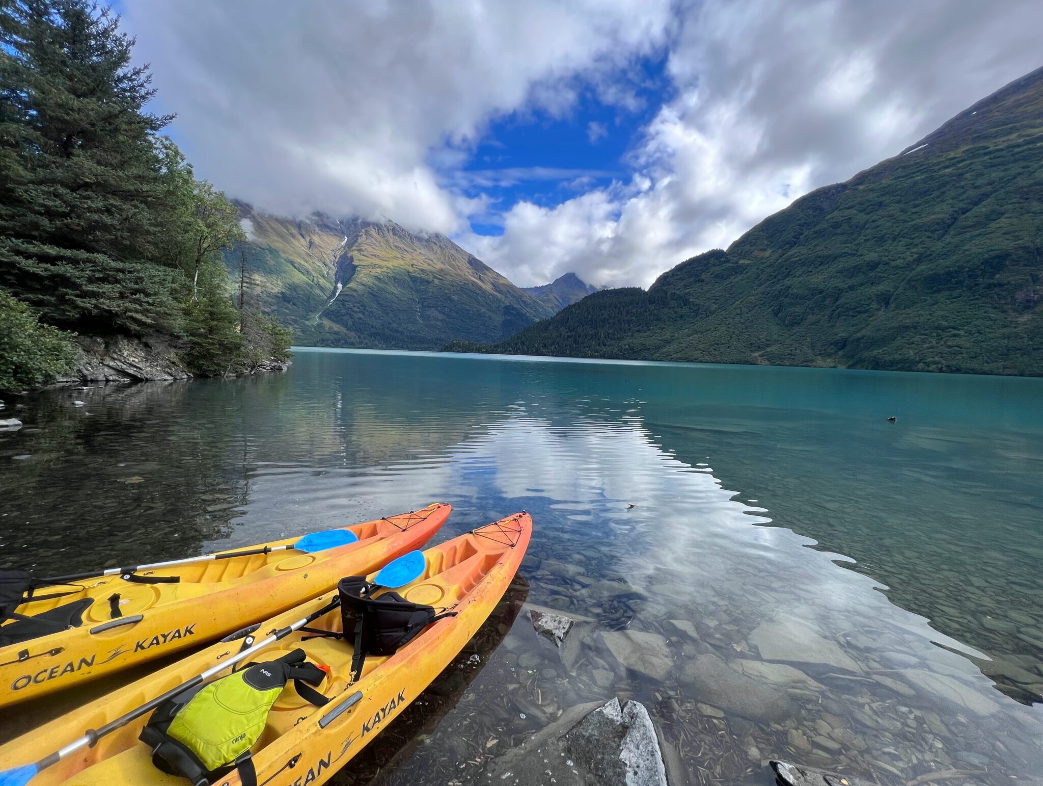 Two kayaks on the shore of glacial Grant Lake in the heart of the Chugach Mountains in Alaska