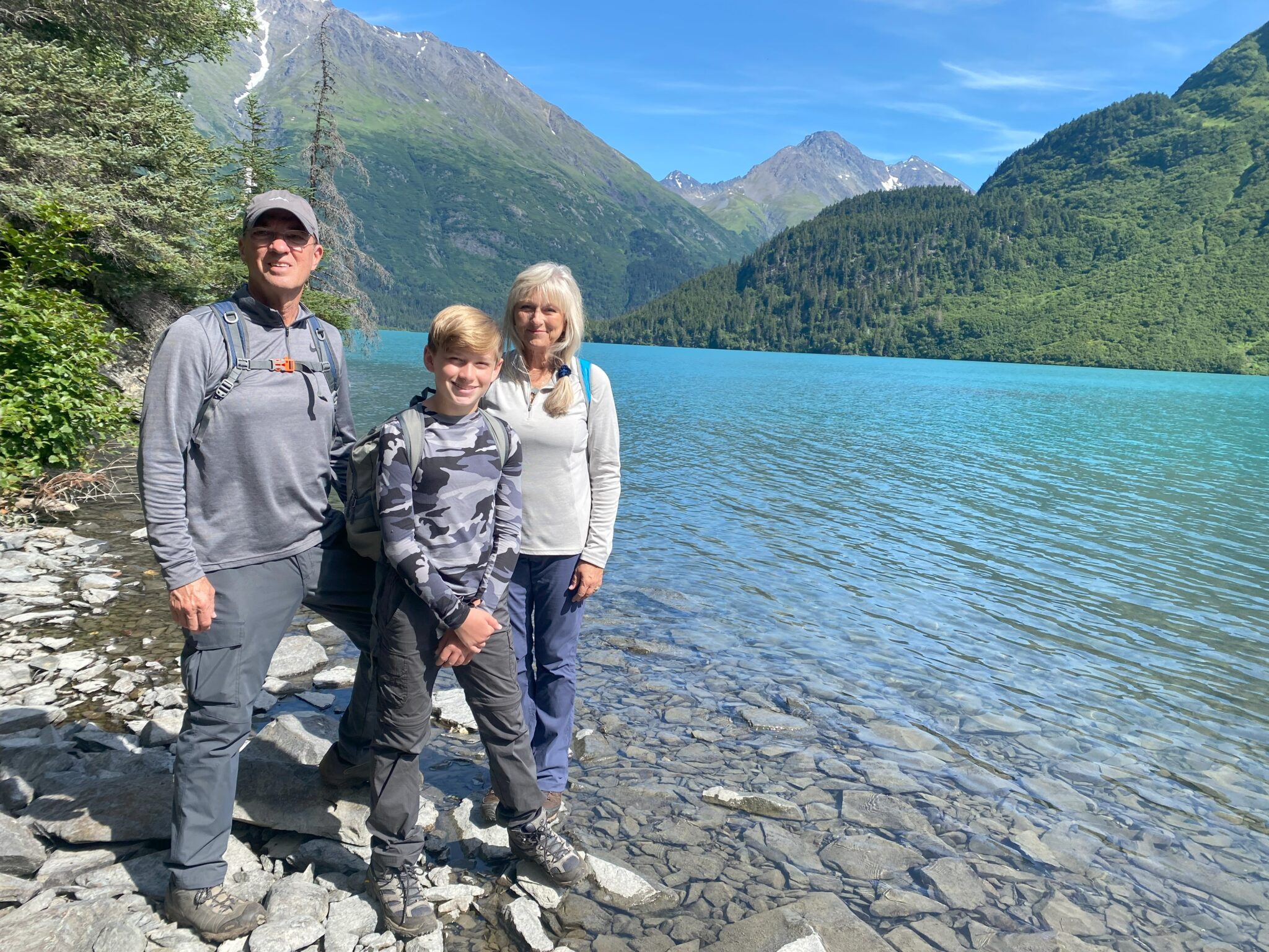 Family hiking to a remote turquoise lake surrounded by Chugach Mountains in Alaska